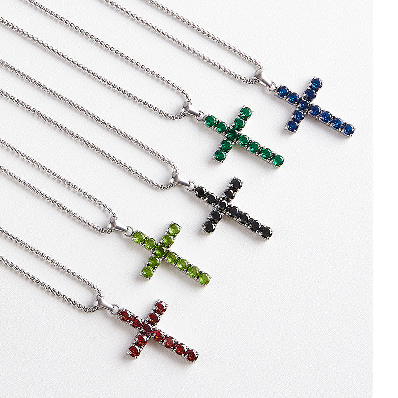 Four silver cross pendant necklaces with gemstone-studded pendants in red, green, black, and blue, arranged diagonally on a white background.