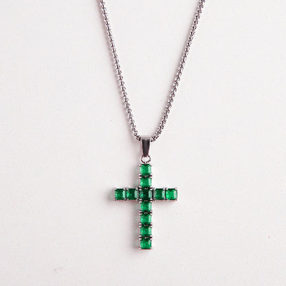 A silver cross pendant necklace adorned with multiple rectangular green gemstones, suspended from a silver ball chain against a plain white background.