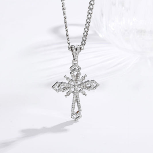 A silver-toned cross pendant necklace paved with small clear stones, hanging from a matching chain on a clean white background.