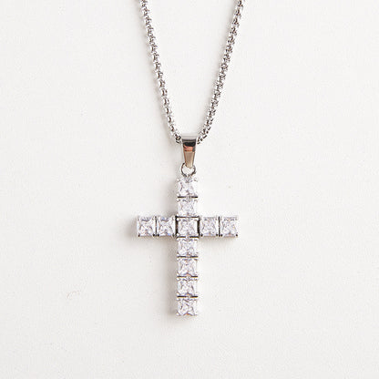 A silver cross pendant necklace adorned with clear square-cut stones, hanging from a silver chain against a plain white background.