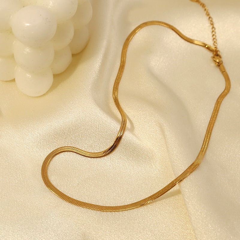 Gold Herringbone Chain Necklace draped on white fabric — elegant everyday necklace