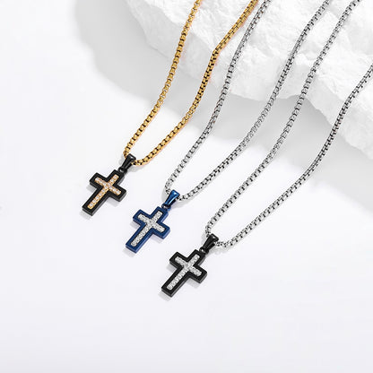 Three cross pendant necklaces with black bezels and clear crystal-like detailing, shown on gold, blue, and silver chains against a white background with a white rock prop.