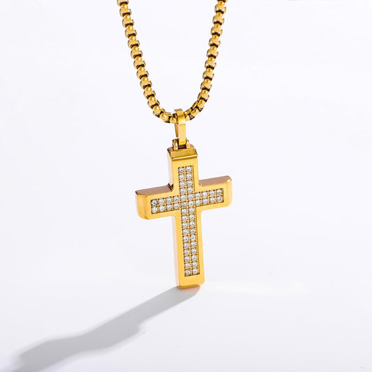 A gold cross pendant necklace with a channel-set row of clear cubic zirconia stones on the front, suspended from a gold box chain against a white background.