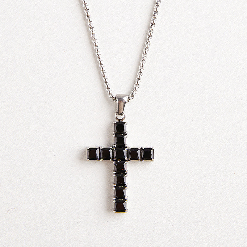 A silver cross pendant necklace with a row of black square crystals, suspended from a silver ball chain against a plain white background.