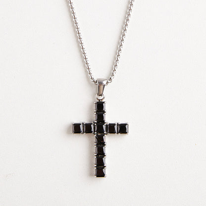 A silver cross pendant necklace with a row of black square crystals, suspended from a silver ball chain against a plain white background.