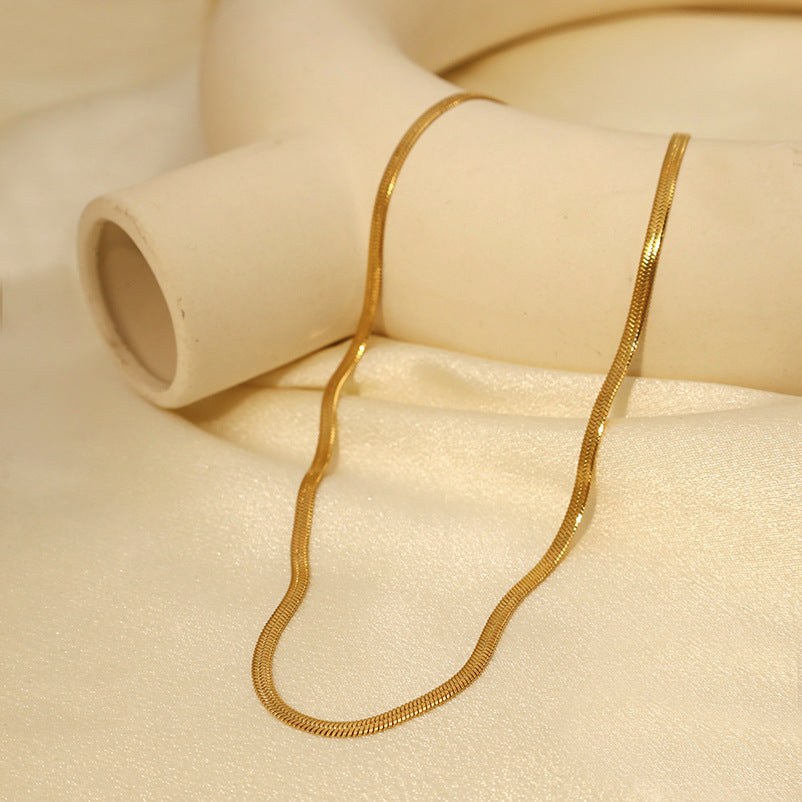 Gold Herringbone Chain Necklace styled with white decor — minimalist gold chain