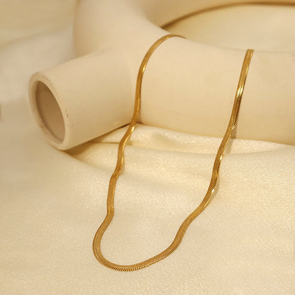 Gold Herringbone Chain Necklace styled with white decor — minimalist gold chain